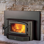 Regency i2500 wood-burning fireplace insert with a glowing orange fire inside, set against a stone wall and hearth.